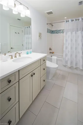 Full bathroom featuring shower / tub combo with curtain, light tile patterned floors, and vanity