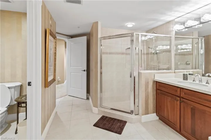 Master bathroom featuring wallpapered walls, vanity, a shower stall, and tile patterned flooring