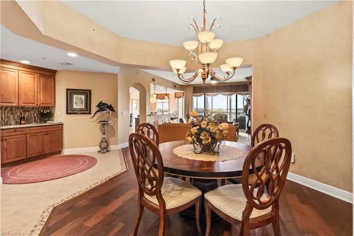 Dining room area with dark wood-type flooring, a chandelier, arched walkways, and recessed lighting