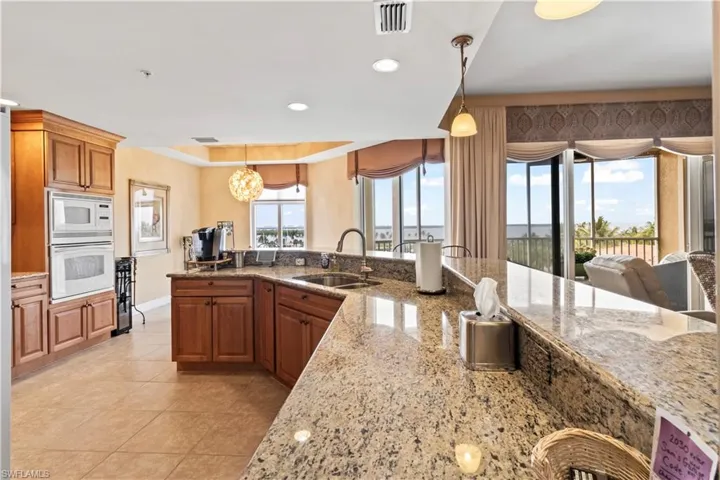 Kitchen with white appliances, light tile patterned floors, pendant lighting, brown cabinetry, and recessed lighting