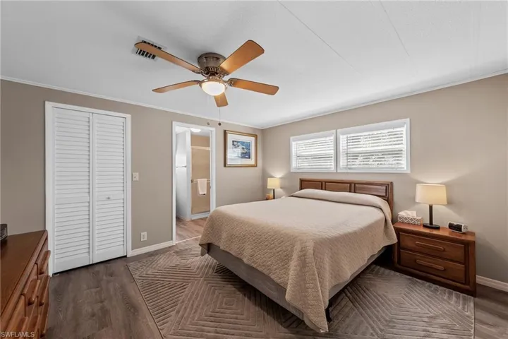 Bedroom with ensuite bathroom, dark wood finished floors, a closet, a ceiling fan, and baseboards