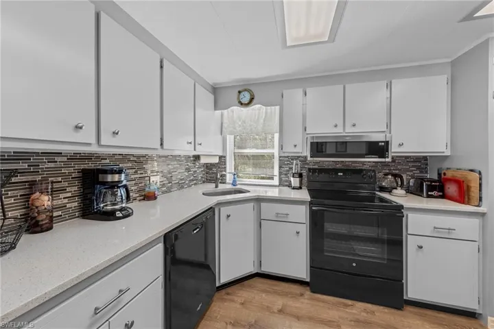 Kitchen with white cabinets, tasteful backsplash, a sink, and black appliances
