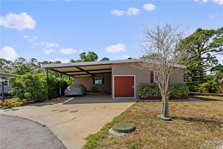 Ranch-style home featuring a carport, driveway, and a front yard