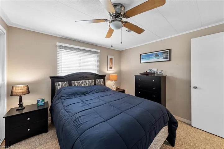 Bedroom with light carpet, baseboards, crown molding, and ceiling fan