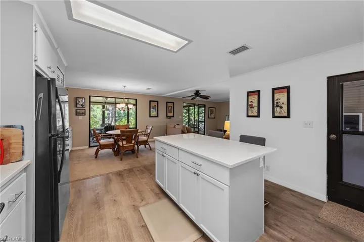 Kitchen with light wood-style floors, freestanding refrigerator, light countertops, and white cabinets