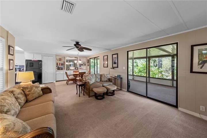 Living room with visible vents, baseboards, a ceiling fan, and light colored carpet