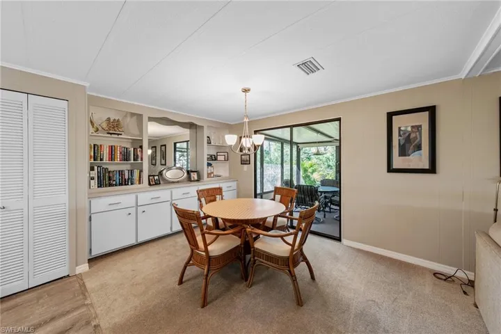 Dining space with light colored carpet, ornamental molding, visible vents, baseboards, and a notable chandelier
