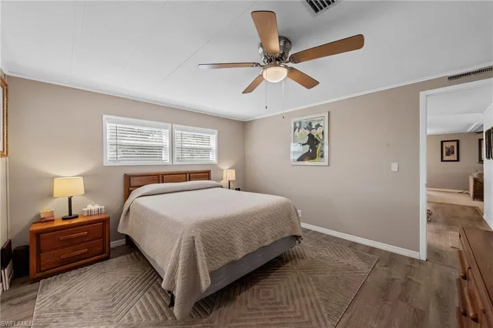 Bedroom featuring ceiling fan, visible vents, baseboards, and wood finished floors