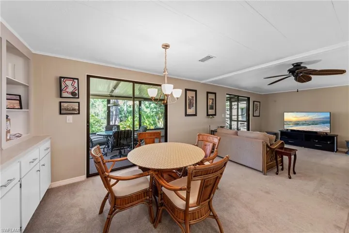 Dining space featuring light carpet, crown molding, a ceiling fan, and visible vents