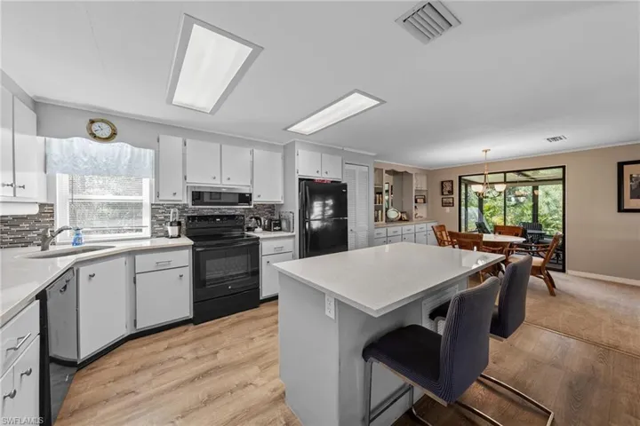 Kitchen with visible vents, a sink, backsplash, and black appliances