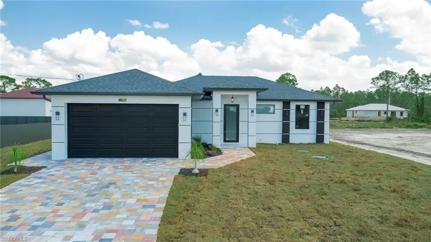 View of front of property with a garage, a front lawn, stucco siding, and driveway