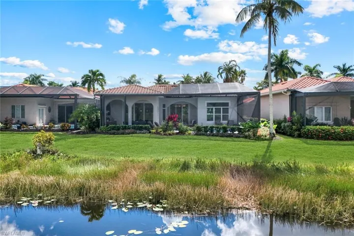 View of front of home with glass enclosure, a front lawn, and a water view