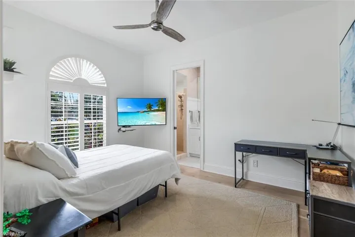 Bedroom with light wood finished floors, ceiling fan, and ensuite bath