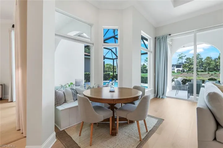 Dining area with a sunroom, light wood finished floors, and ornamental molding