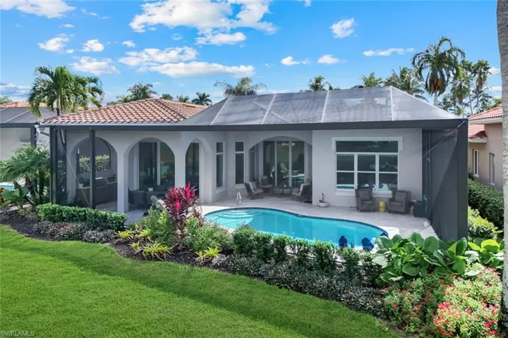 Rear view of property with stucco siding, an outdoor pool, a patio, and a lawn