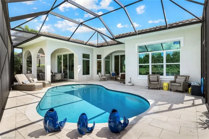 Back of property featuring a sunroom, stucco siding, and an outdoor pool