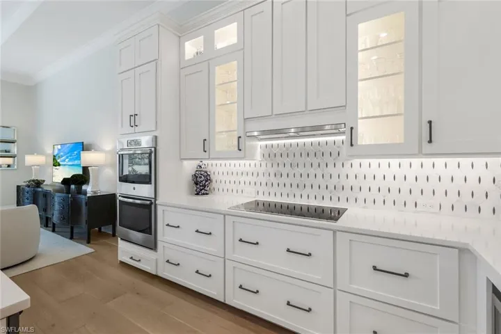 Kitchen featuring ornamental molding, white cabinets, tasteful backsplash, and stainless steel double oven
