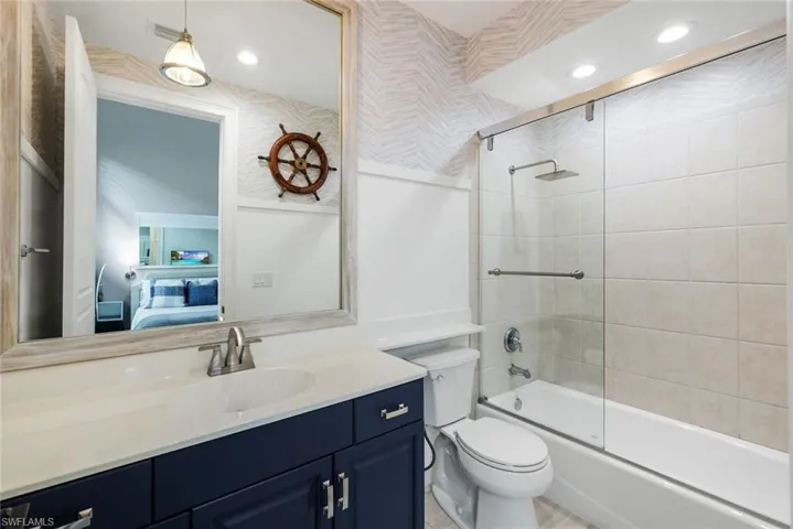 Bathroom featuring connected bathroom, vanity, shower / bath combination with glass door, and recessed lighting