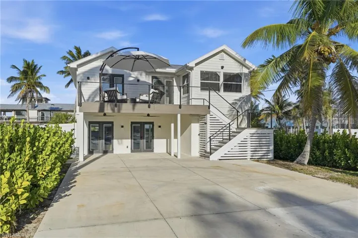View of front facade featuring french doors, stucco siding, stairway, and a patio area Virtually Edited