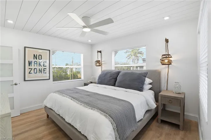 Bedroom with wooden ceiling, multiple windows, wood finished floors, and ceiling fan Virtually Edited