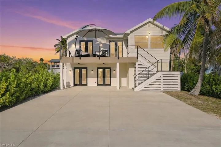 View of front of house featuring french doors, stucco siding, stairs, concrete driveway, and a patio area Virtually Enhanced