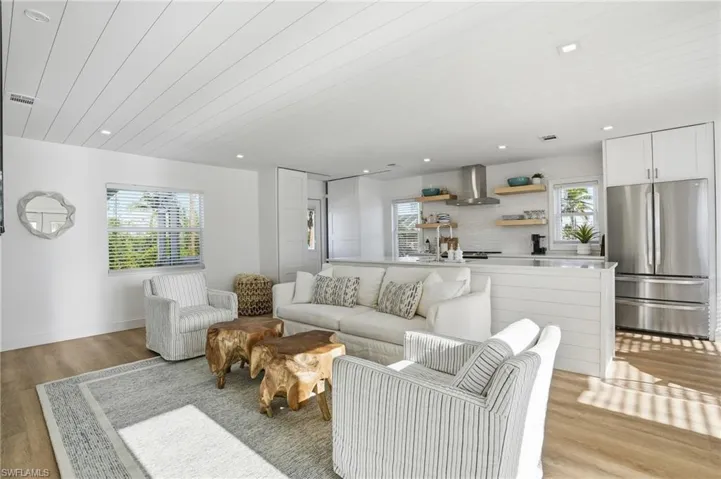 Living area featuring light wood-type flooring, plenty of natural light, and recessed lighting Virtually Edited