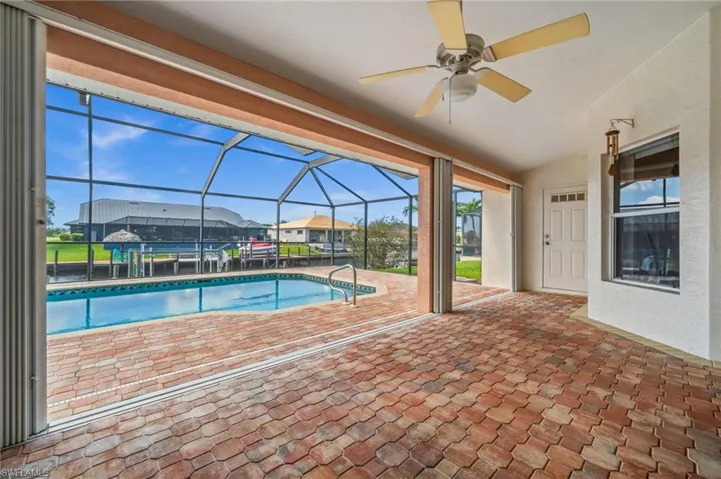 Outdoor pool featuring glass enclosure, a patio, and a sunroom
