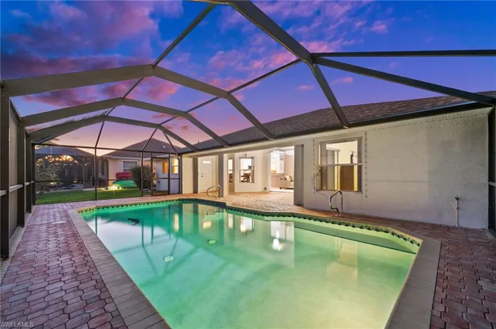 Outdoor pool featuring a sunroom, glass enclosure, and a patio area
