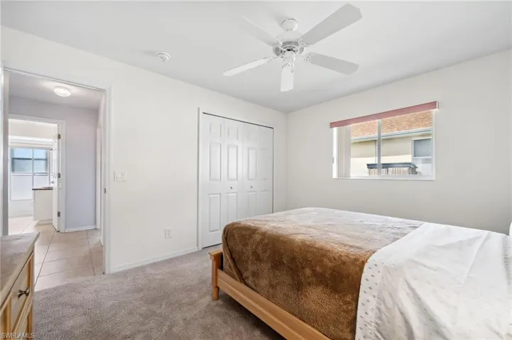 Bedroom with light colored carpet, a closet, and ceiling fan