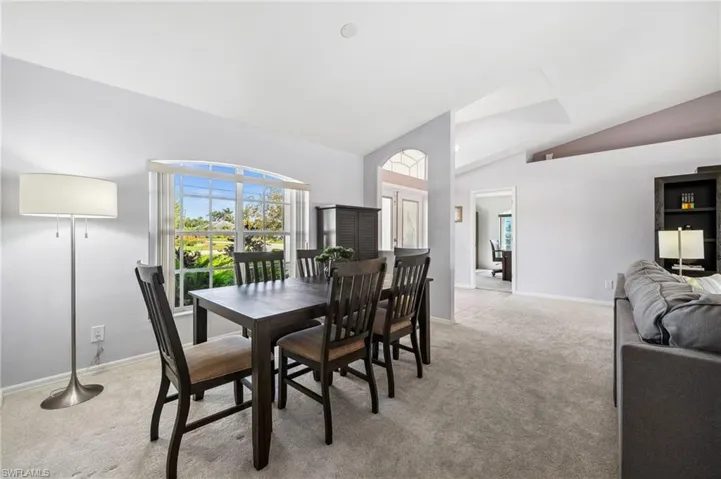 Dining space with light carpet and high vaulted ceiling