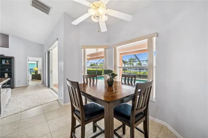 Dining space featuring a sunroom, healthy amount of natural light, light tile patterned floors, a ceiling fan, and high vaulted ceiling