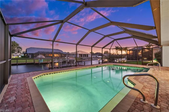 Pool at dusk with an outdoor pool, a lanai, and a sunroom