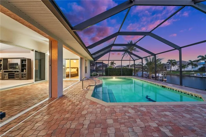 Outdoor pool featuring a patio, a lanai, a sunroom, and a water view