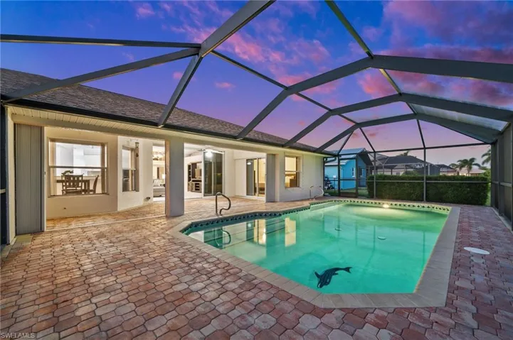 Outdoor pool featuring a sunroom, glass enclosure, and a patio
