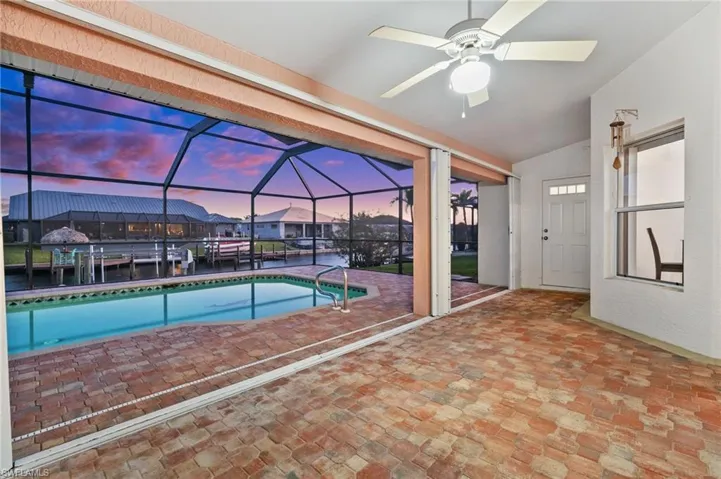 Swimming pool featuring a sunroom, ceiling fan, and a water view