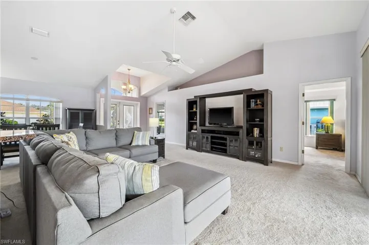 Living area with carpet, ceiling fan, a chandelier, and high vaulted ceiling