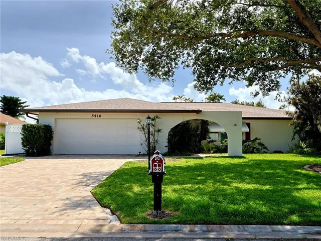 Single-story residence featuring a two-car garage, paver driveway, and a manicured front lawn