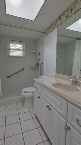 Bathroom featuring a white vanity with paneling and brushed nickel hardware, a light-toned countertop with an integrated sink, and a large wall-mounted mirror