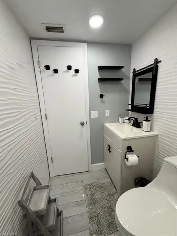Bathroom with vanity, light wood-type flooring, and tile walls