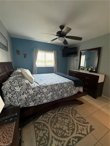 Bedroom with light tile patterned floors and a ceiling fan