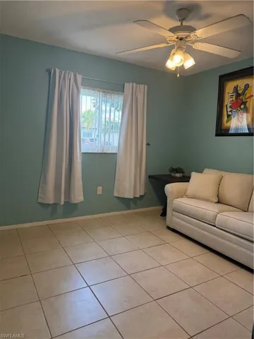 Living room with ceiling fan and light tile patterned flooring