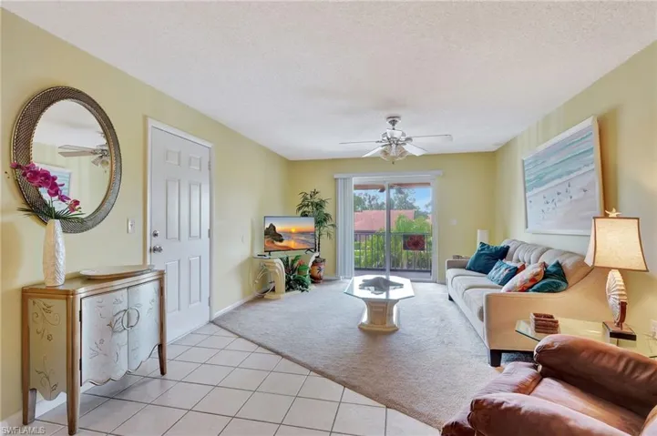 Living room with light tile patterned floors, a textured ceiling, and ceiling fan