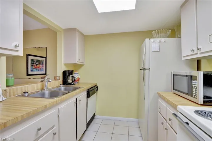 Kitchen featuring sink, light tile patterned floors, dishwasher, and white cabinets