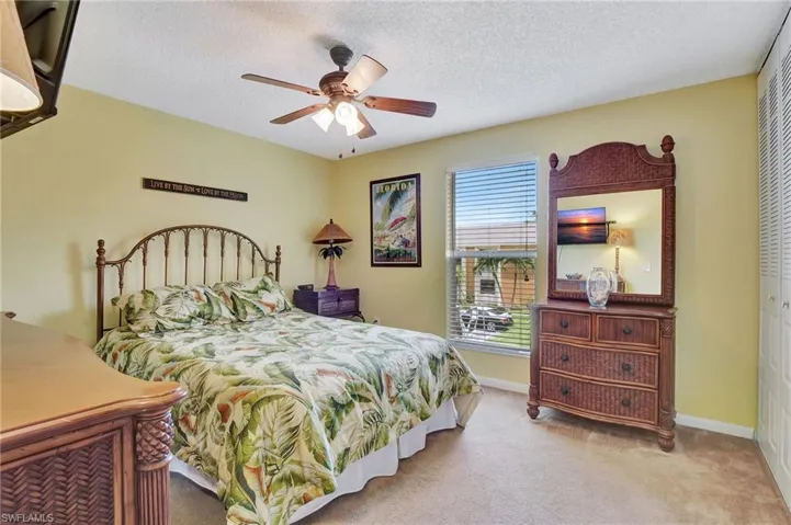 Bedroom with light colored carpet, a closet, a textured ceiling, and ceiling fan