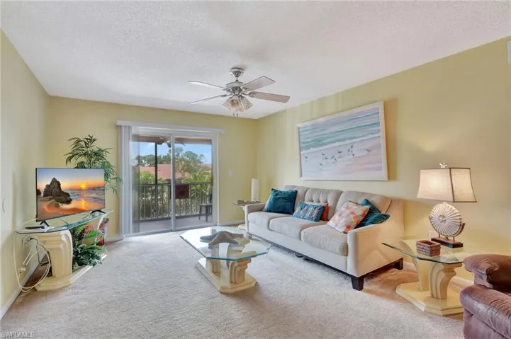 Living room featuring carpet floors, a textured ceiling, and ceiling fan