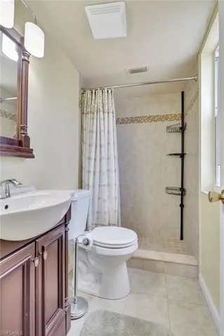 Bathroom with vanity, walk in shower, toilet, and tile patterned floors