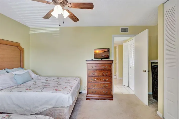 Bedroom with a closet, ceiling fan, and light colored carpet