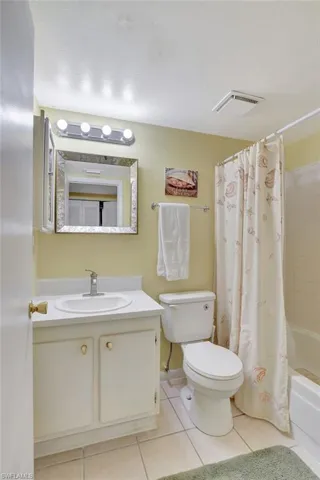 Full bathroom with tile patterned flooring, shower / bath combo, a textured ceiling, toilet, and vanity
