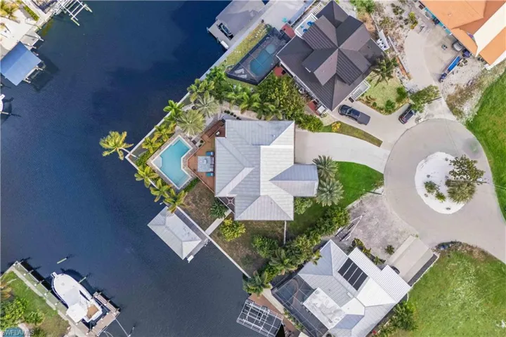 Tropical Elegance Meets Waterfront Living: Vibrant landscaping, swaying palms, and sparkling blue waters set the scene for ultimate relaxation.