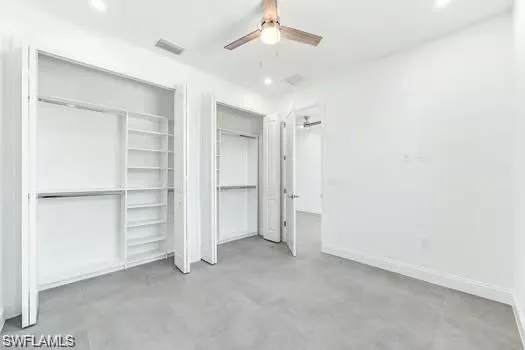 Bedroom on main entrance side with finished concrete floors, two custom closets, ceiling fan, and recessed lighting